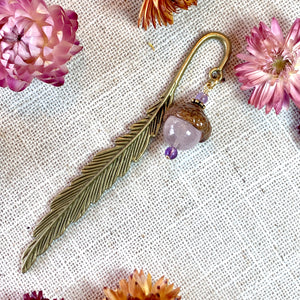 a close up of a pair of earrings with flowers in the background