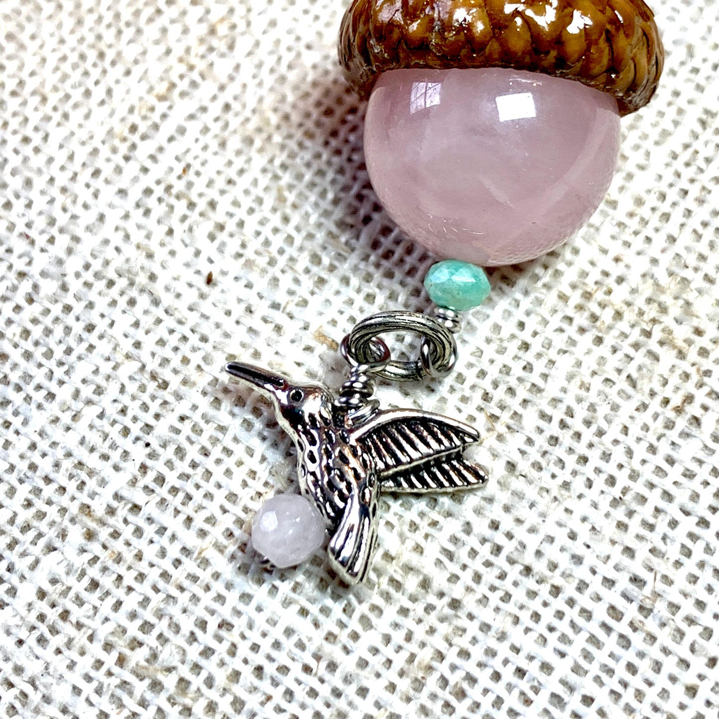 a necklace with a bird charm and a bead