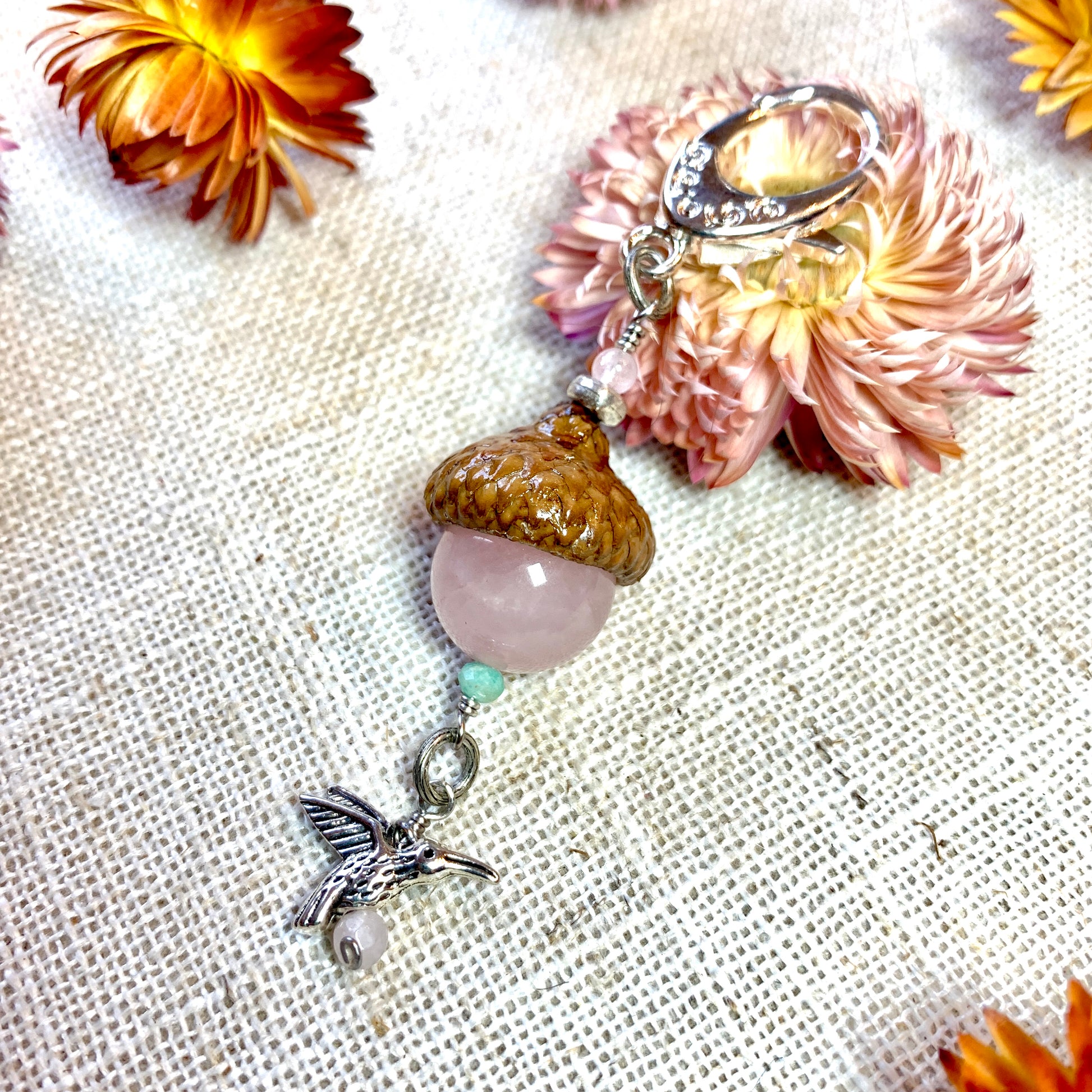 a close up of a necklace on a table with flowers